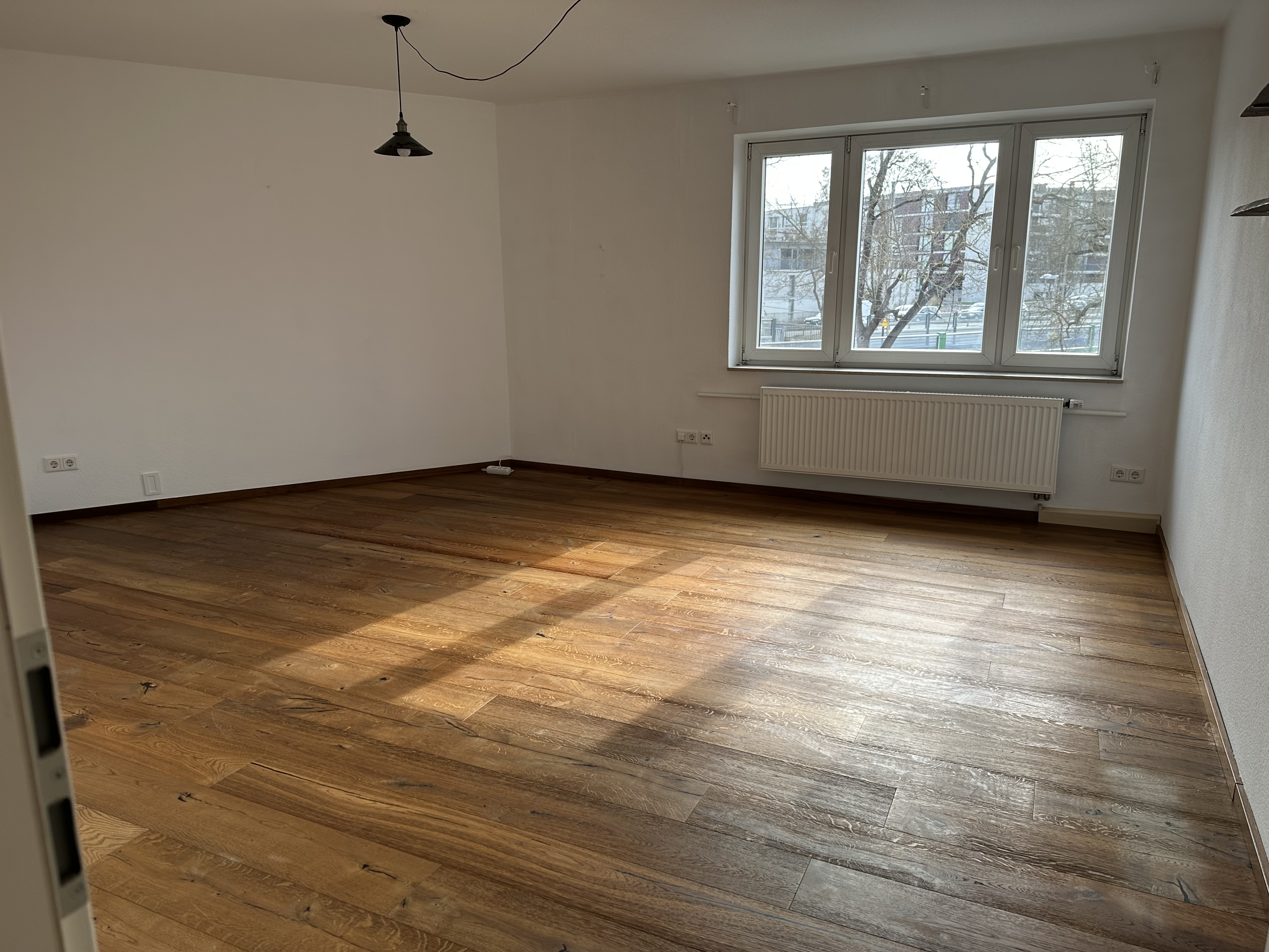 Wohnzimmer mit breiter Fensterfront und Echtholzparkett